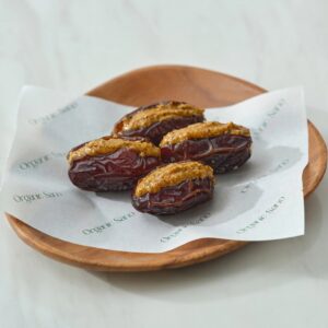 Organic Sano pistachio and pumpkin seed butter stuffed dates on a wooden plate